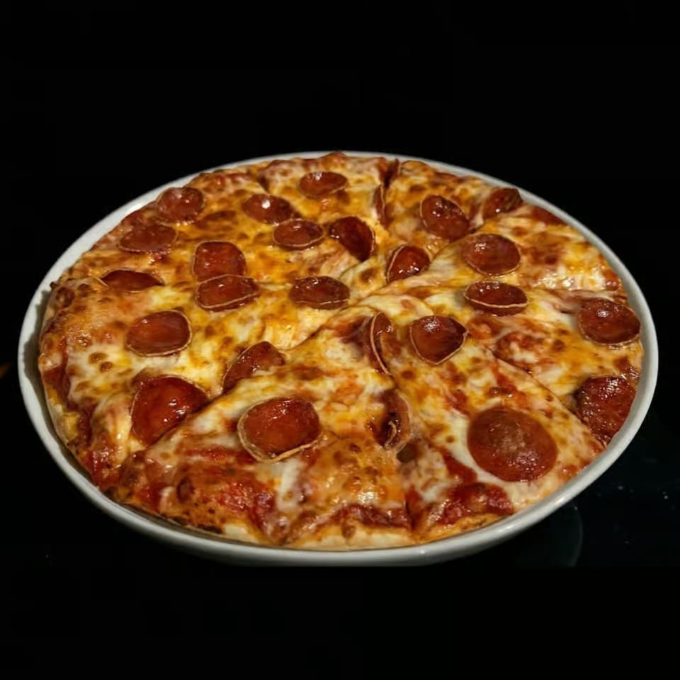 A whole pepperoni pizza, sliced into eight pieces, on a white plate against a dark background.