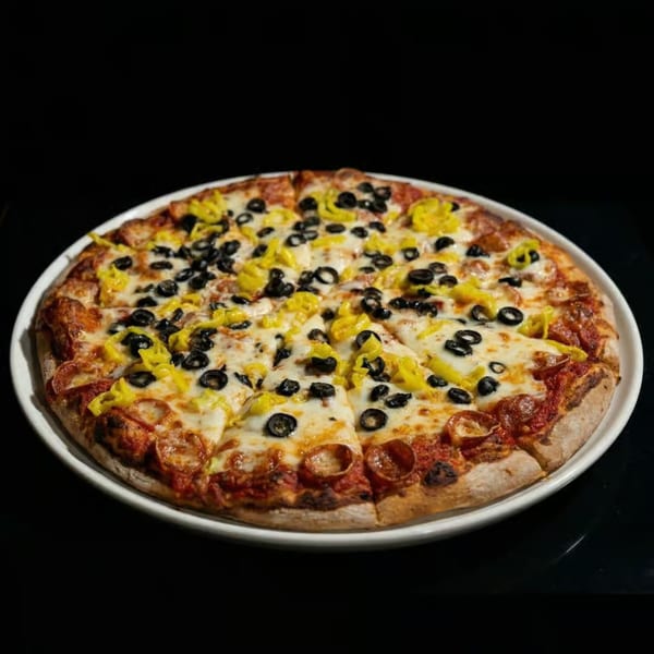 Pepperoni pizza with black olives and banana peppers on a white plate against a dark background.
