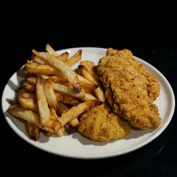 A white plate holds golden-brown french fries and crispy fried chicken tenders against a dark background.